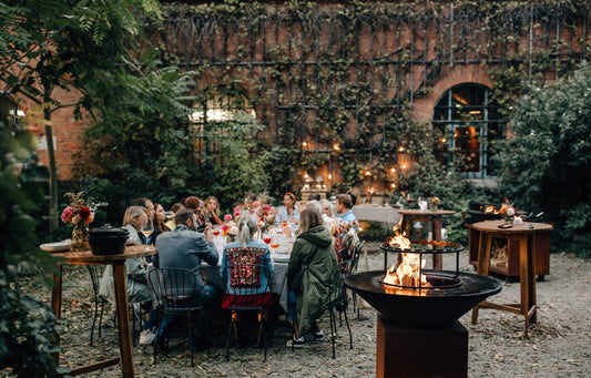 Gartenfest am Abend mit langer Tafel und Feuerplatte im Innenhof