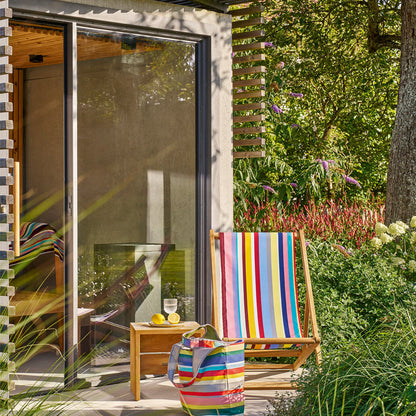 Weishäupl Cabin Liegestuhl bunt gestreift am Gartenhaus mit Multibag und Beistelltisch