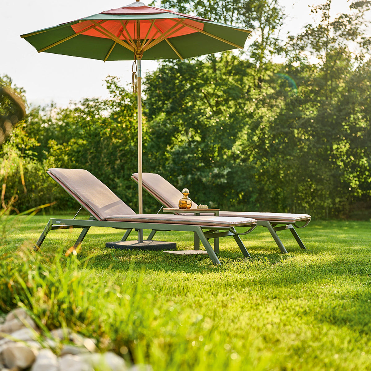 Zwei Weishäupl Minu Sonnenliegen im Garten mit Klassiker-Schirm
