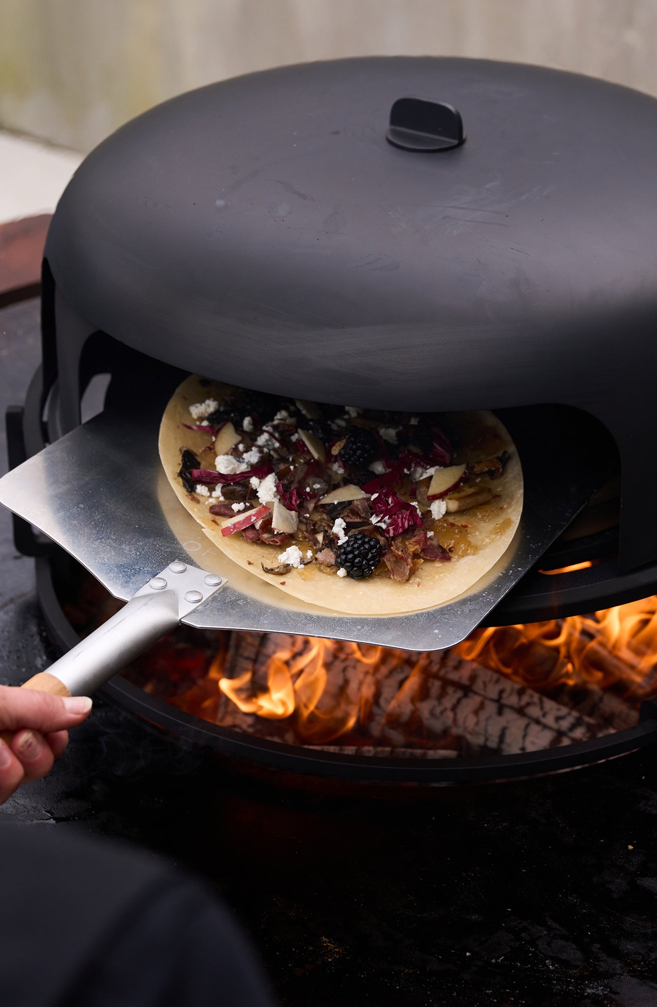 OFYR Pizza Oven 100 auf der OFYR Feuerplatte in mediterranem Garten