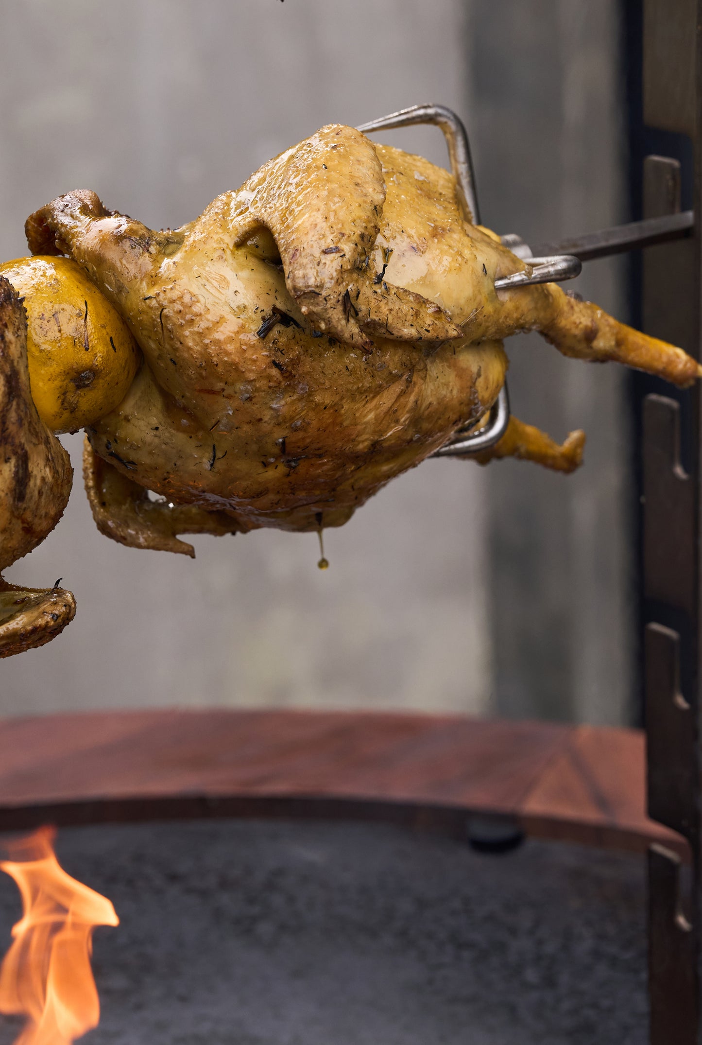 Hähnchen dreht sich am Spieß des OFYR Rotisserie Set über dem Feuer