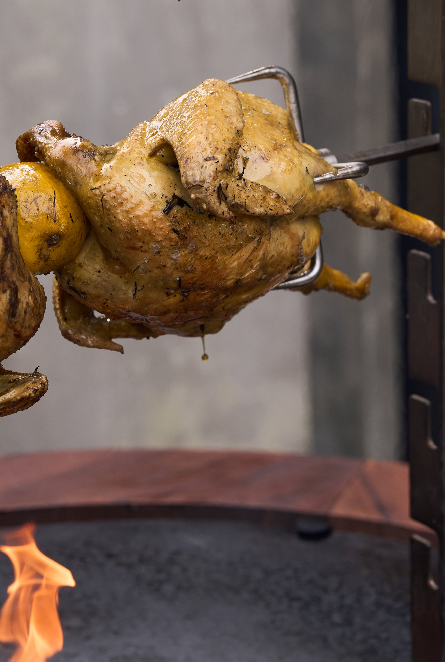 Hähnchen dreht sich am Spieß des OFYR Rotisserie Set über dem Feuer